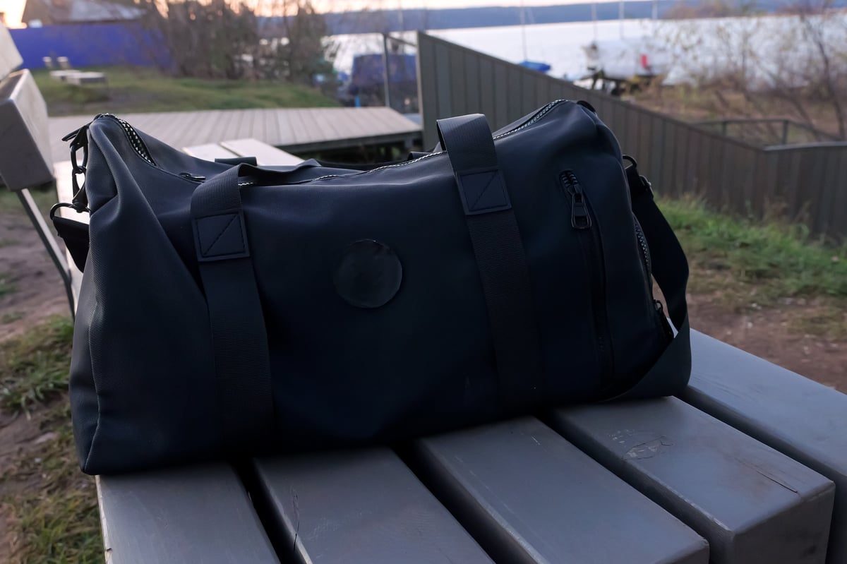 Black duffel bag on a wooden bench