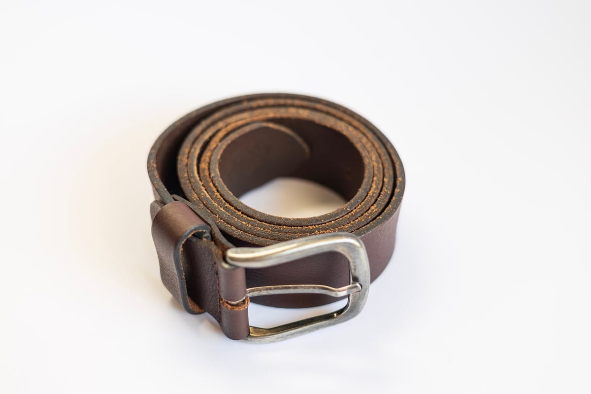 Rolled brown leather belt with a metal buckle