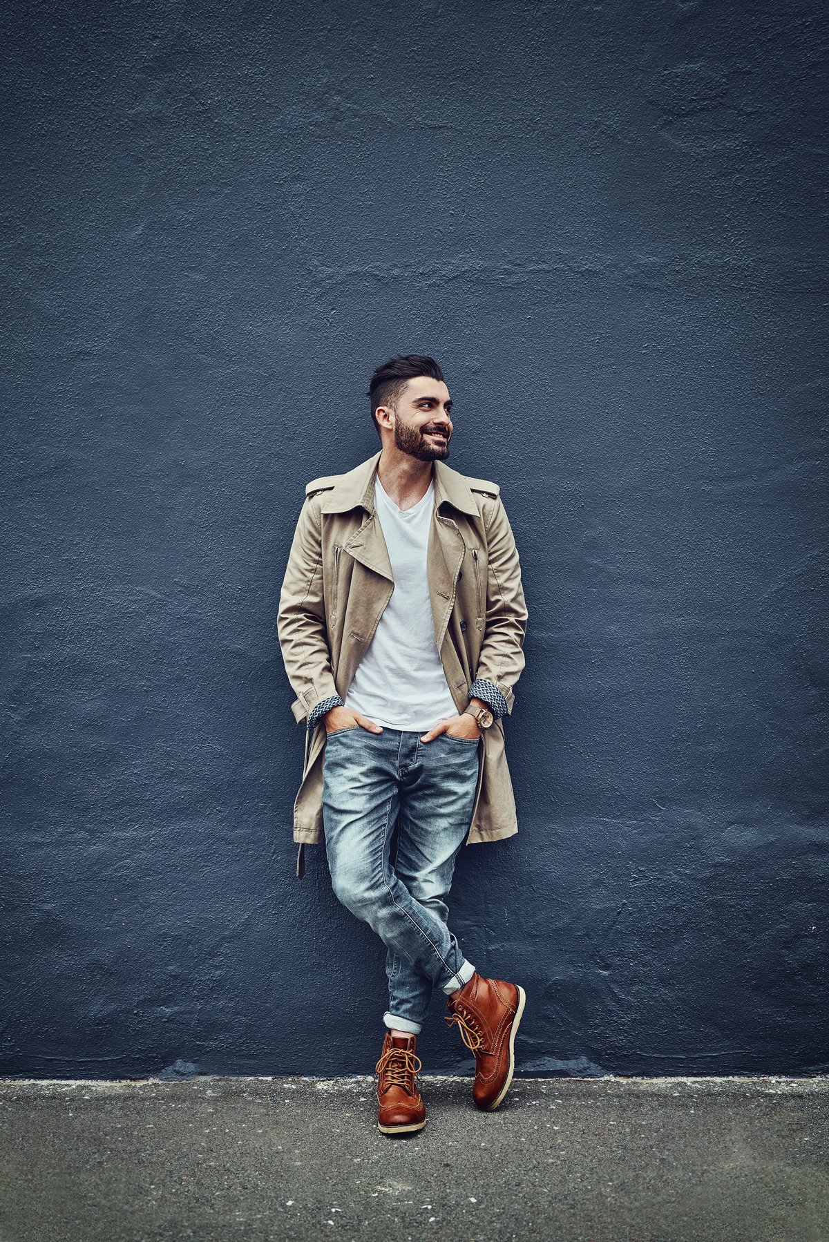 Young man in urban wear posing against a gray wall